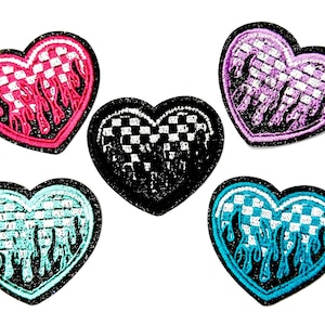 May include: Five heart-shaped embroidered patches. Each patch features a checkered pattern and flame-like design. Colors include pink, black, purple, teal, and blue. The patches have a glittery border.