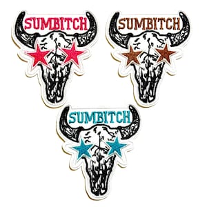 May include: Embroidered patches featuring a steer skull design with the word "SUMBITCH" above the skull. Each patch has star-shaped sunglasses in red, brown, or teal. The patches have a white border.
