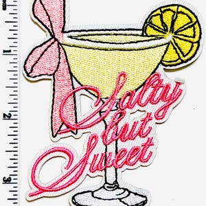May include: Embroidered patch featuring a cocktail with a lemon slice and a pink bow. The patch has the text "Salty but Sweet" in pink script. The cocktail glass is yellow and white.