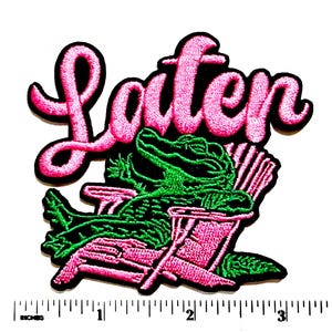 May include: An embroidered patch featuring a green alligator lounging in a pink Adirondack chair. Above the alligator, the word "Later" is stitched in pink cursive script. A ruler at the bottom shows the patch is approximately 3.5 inches wide.