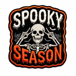 May include: An embroidered patch with a black background and an orange border. It features a white skeleton making a peace sign with both hands. The text SPOOKY is embroidered in white above the skeleton, and the word SEASON is in orange below.