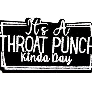 May include: Black and white patch with the phrase "It's A THROAT PUNCH Kinda Day" in white script. The patch is approximately 2 inches in height and has a decorative border.