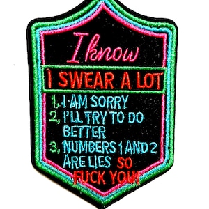 May include: Embroidered black patch with a shield shape, featuring the text "I know I SWEAR A LOT." Additional text includes "1. I AM SORRY, 2. I'LL TRY TO DO BETTER, 3. NUMBERS 1 AND 2 ARE LIES SO FUCK YOU!" The patch has a green, pink, and blue border.