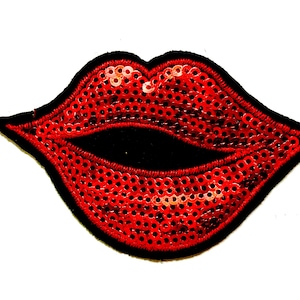 May include: A red sequined lips patch with a black velvet center and a black border. The patch measures approximately 2 inches in height.