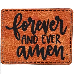 May include: A rectangular brown leather patch with black stitched edges and the black text "forever AND EVER amen." printed in the center. A white ruler is positioned along the left side, showing the patch height is approximately 2.25 inches.
