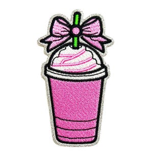 May include: An embroidered patch shaped like a pink drink in a cup with a white whipped cream topping, a bright green straw, and a large pink bow at the top. The design features black outlines and a silver-colored border on a white background.