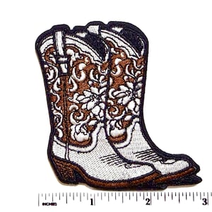 May include: Embroidered patch featuring a pair of cowboy boots. The boots are white with brown and black accents, and detailed floral embroidery. The patch is approximately 3 inches in length.