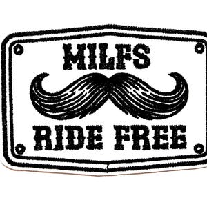 May include: A white patch with a black border and the text "MILFS RIDE FREE" above a large black mustache. The patch is rectangular with rounded corners and a decorative border.