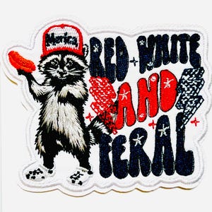 May include: Embroidered patch featuring a raccoon wearing a red hat with "Merica" on it, holding a hot dog. The patch reads "Red, White, and Feral" in red and blue lettering. The patch measures approximately 3 inches tall.