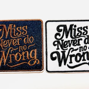 May include: Two embroidered patches with the phrase "Miss Never do no Wrong." One patch is navy blue with gold lettering, the other is white with black lettering. Both have a rectangular shape with rounded corners.