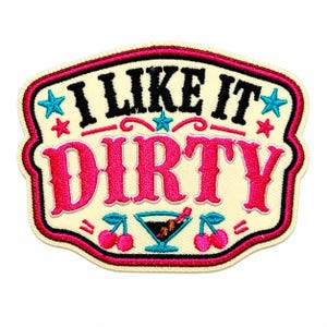 May include: An embroidered patch with a cream-colored background and a pink and black border. The text reads I LIKE IT in black and DIRTY in large pink letters. The design includes four small blue and pink stars, two pairs of pink cherries, and a martini glass.