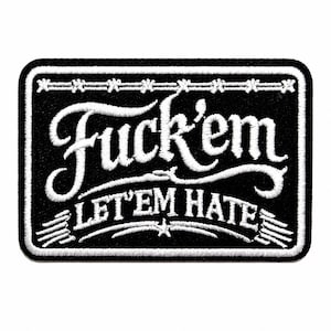 May include: A rectangular embroidered patch with a black background and white border. The text "Fuck'em" is in large script, with "LET'EM HATE" in smaller block letters below. A barbed wire graphic runs across the top and bottom edges.