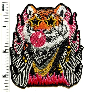 May include: Embroidered patch featuring a tiger with star-shaped sunglasses, a red bubble, and a gold chain. The tiger has orange and black stripes, with pink and white accents. The patch measures approximately 3 inches in height.