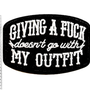 May include: Black embroidered patch with white text that reads "GIVING A FUCK doesn't go with MY OUTFIT". The patch is approximately 2.5 inches long and 1.5 inches tall. The patch has a black background and white stitching.