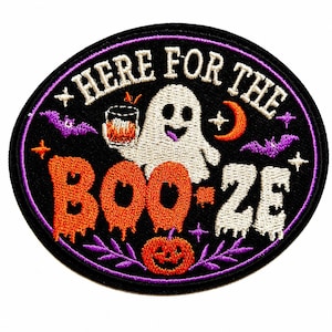 May include: An oval embroidered patch with a black background and a purple border. It features a white ghost holding a glass of orange liquid, an orange pumpkin, purple bats, and stars. The text reads HERE FOR THE BOO-ZE in white and orange.