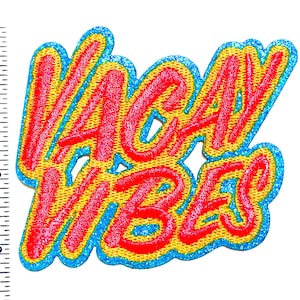 May include: A colorful embroidered patch with the words "VACAY VIBES" in red, outlined in yellow, and bordered with blue glitter. The patch is approximately 3 inches wide.