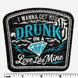 May include: Black embroidered patch with the text "I Wanna Get You Drunk On A Love Like Mine" in white and teal. A teal diamond graphic is centered below the word "Drunk". The patch has a black border with white stitching.