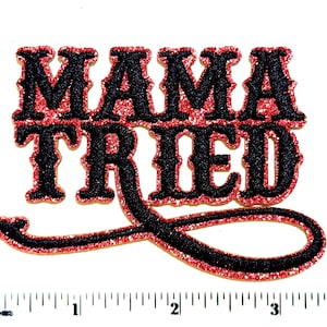 May include: A glittery patch with the words "MAMA TRIED" in black letters with red glitter trim. The patch has a decorative cursive tail extending from the word "TRIED". The patch is on a white background.