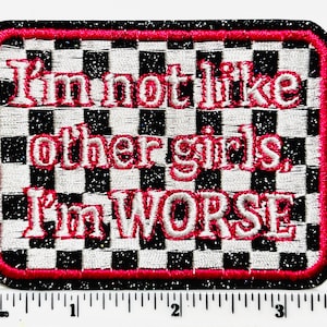 May include: Embroidered patch with the text "I'm not like other girls, I'm WORSE" in red thread. The patch has a black and white checkered background, a red border, and a black glittery edge. The patch is rectangular.