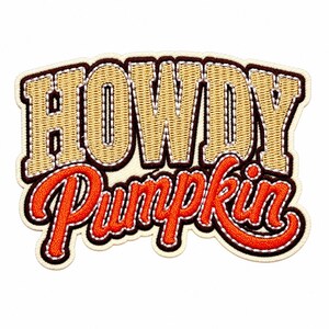 May include: An embroidered patch featuring the text HOWDY in gold block letters with a dark brown border, positioned above the word Pumpkin in orange cursive script with a dark brown outline, all set against a cream-colored fabric background.