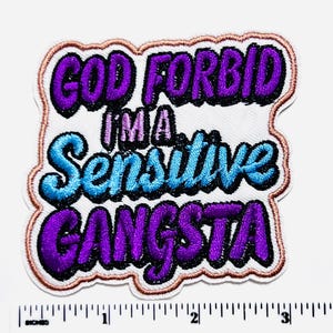 May include: Embroidered patch with the text "GOD FORBID I'M A Sensitive GANGSTA" in purple, blue, and black lettering. The patch has a white background with a brown border and is approximately 3 inches wide.