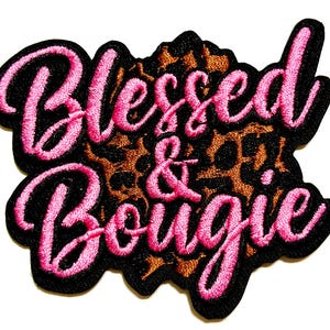 May include: Embroidered patch with the words "Blessed & Bougie" in pink script lettering. The text is outlined in black and set against a leopard print background. The patch has a black border.