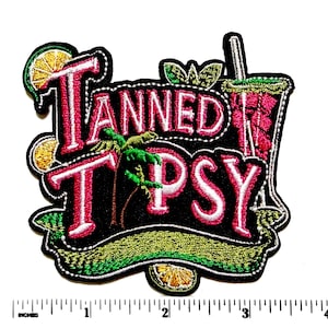 May include: Embroidered patch with the words "TANNED TIPSY" in red and white, featuring a palm tree, cocktail, and citrus slices. The patch is outlined in black with a green and yellow border. The patch measures approximately 3 inches wide.