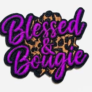 May include: Embroidered patch with the words "Blessed & Bougie" in purple script with a black outline. The background is a leopard print pattern in brown and black.