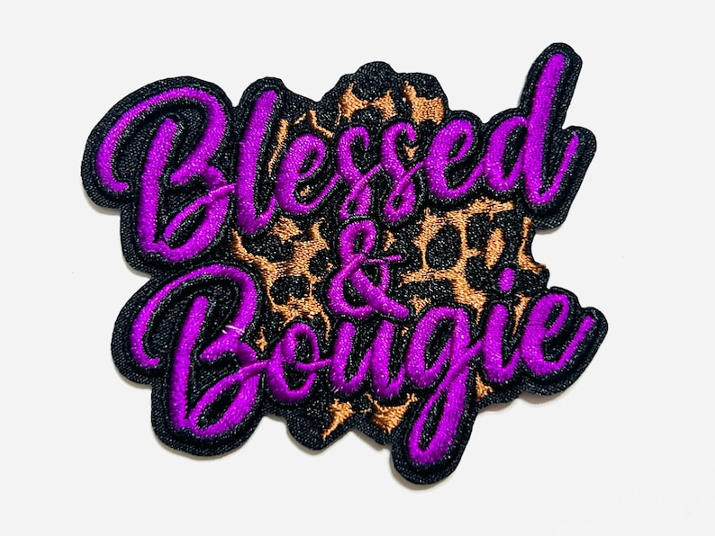 May include: Embroidered patch with the words "Blessed & Bougie" in purple script with a black outline. The background is a leopard print pattern in brown and black.