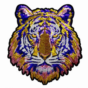 May include: A tiger head patch crafted from shimmering sequins in vibrant shades of blue, yellow, white, and pink. The design features the detailed facial features of a tiger, including pointed ears, intense yellow eyes, and whiskers.