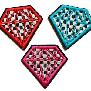 May include: Three diamond-shaped embroidered patches. One is red, one is teal, and one is pink. Each has a black and white checkered pattern inside and a black border. The patches are on a white background.