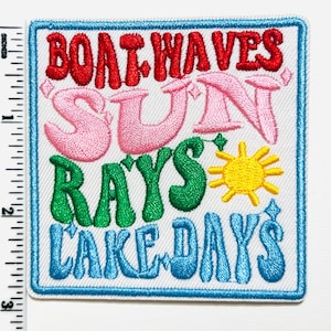 May include: Embroidered patch with the words "BOAT WAVES SUN RAYS LAKE DAYS" in red, pink, green, and blue. A yellow sun graphic is also included. The patch is approximately 3 inches tall and 3 inches wide.