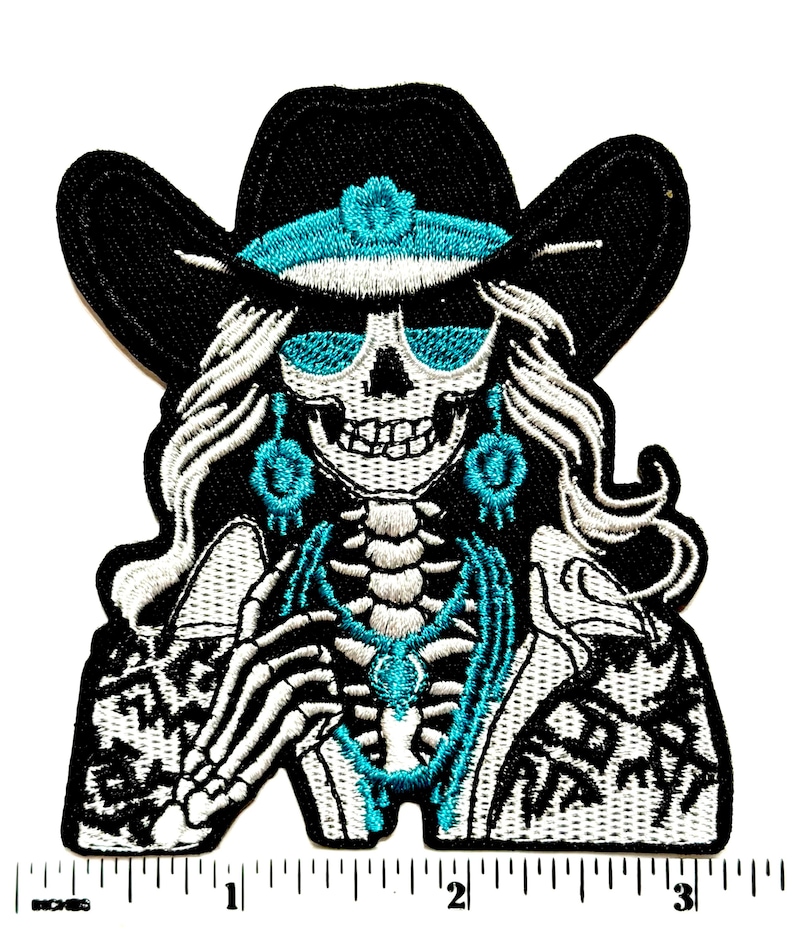May include: Embroidered patch featuring a skeleton wearing a black cowboy hat with turquoise accents and sunglasses. The skeleton has long white hair and turquoise jewelry. The patch has a black and white patterned jacket and a skeleton torso.