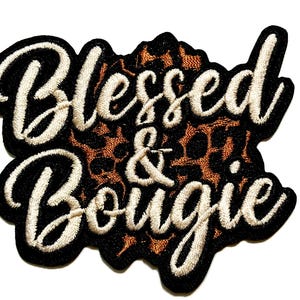 May include: Embroidered patch with the words "Blessed & Bougie" in a cursive font. The text is in off-white thread, outlined in black, and set against a leopard print background.