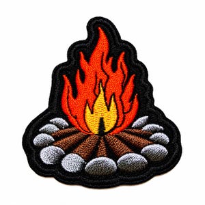 May include: An embroidered patch featuring a campfire design with bright orange and yellow flames rising from brown logs arranged in a circle. The base of the fire is surrounded by grey stones, all outlined with a thick black border.
