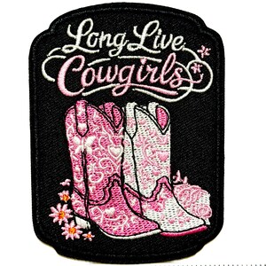 May include: Embroidered patch with the text "Long Live Cowgirls" in white and pink script. The patch features two pink and white cowboy boots with floral detailing, set against a black background. Daisies are at the bottom.