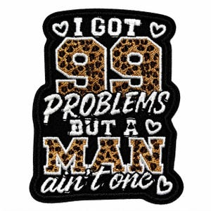 May include: An embroidered patch with a black background featuring the text I GOT 99 PROBLEMS BUT A MAN AIN'T ONE. The numbers 99 and the word MAN are filled with a brown and black leopard print pattern, while the remaining text is white.