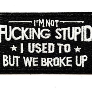 May include: Black rectangular patch with white embroidered text: "I'M NOT FUCKING STUPID * I USED TO * BUT WE BROKE UP". The patch is approximately 2 inches long and 1 inch wide.