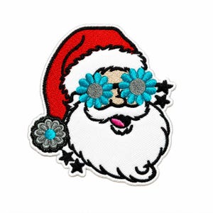 May include: An embroidered patch featuring a Santa Claus face wearing bright blue flower-shaped glasses. Santa has a red hat with a gray flower pom-pom, a white beard, and a small pink tongue sticking out, accented by several black star shapes.