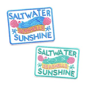 May include: Two rectangular embroidered patches featuring the text SALTWATER SEASHELLS SUNSHINE. The top patch has blue text and a yellow banner, while the bottom patch has teal text and a yellow banner. Both feature pink shells and blue starfish.