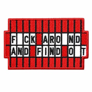 May include: A rectangular embroidered patch featuring a red background with vertical black stripes. The design includes white horizontal bars containing the black text FUCK AROUND AND FIND OUT, with the letters U and O omitted from the words.