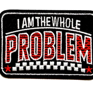 May include: Black rectangular patch with the text "I AM THE WHOLE PROBLEM" in white and red. The word "PROBLEM" is in large, bold, red letters. The patch has a white border and a checkered pattern at the bottom, with red star accents.