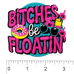 May include: Embroidered patch with the phrase "Bitches be floatin" in pink, black, and white. The patch features a donut, sunglasses, and a tropical drink. The patch is approximately 3 inches wide.