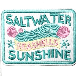 May include: A rectangular patch with a white background and a teal border. The patch features the words "SALTWATER SUNSHINE" in teal, with "SEASHELLS" in yellow. Pink seashells and teal waves are also depicted.