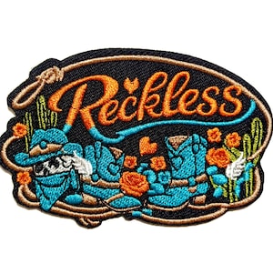 May include: Embroidered patch with the word "Reckless" in orange script, featuring turquoise cowboy boots, a hat, and floral accents on a black background. The patch is outlined in brown and has a rope design.