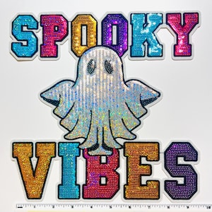 May include: A Halloween-themed patch with the words "SPOOKY VIBES" in colorful, sequined letters. A shimmering, sequined ghost is centered between the words. The patch has a white border and is on a white background.