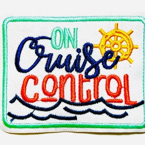 May include: Embroidered patch with the words "ON Cruise CONTROL" in blue, orange, and green. A yellow ship's wheel is in the upper right corner. The patch is approximately 2.5 inches wide and 2 inches tall.