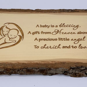 Puede incluir: Un letrero de madera con una imagen tallada de una madre sosteniendo un bebé. El letrero tiene el texto "A baby is a blessing. A gift from Heaven above, A precious little angel To cherish and to love."