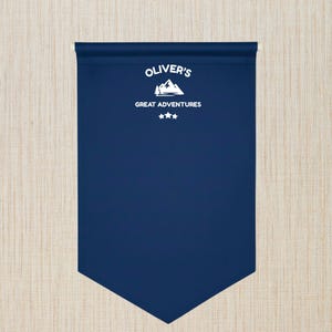 May include: A navy blue pennant banner with white text reading "OLIVER'S GREAT ADVENTURES" above a mountain and tree graphic, with three stars below. The banner has a rolled top and a pointed bottom.