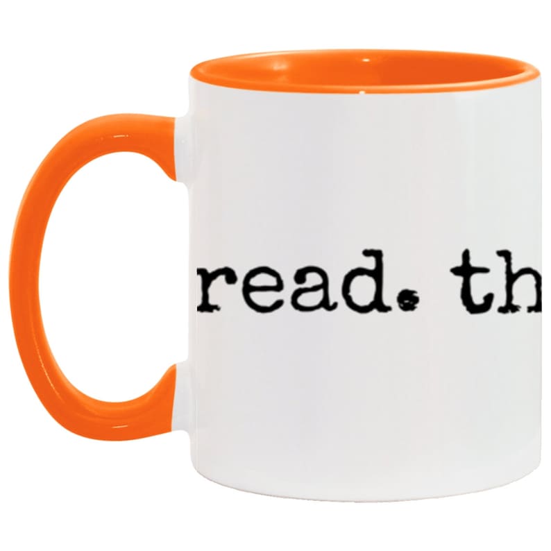 May include: White ceramic mug with an orange rim and handle. The mug has the text "read. the" printed on the front in a typewriter font.